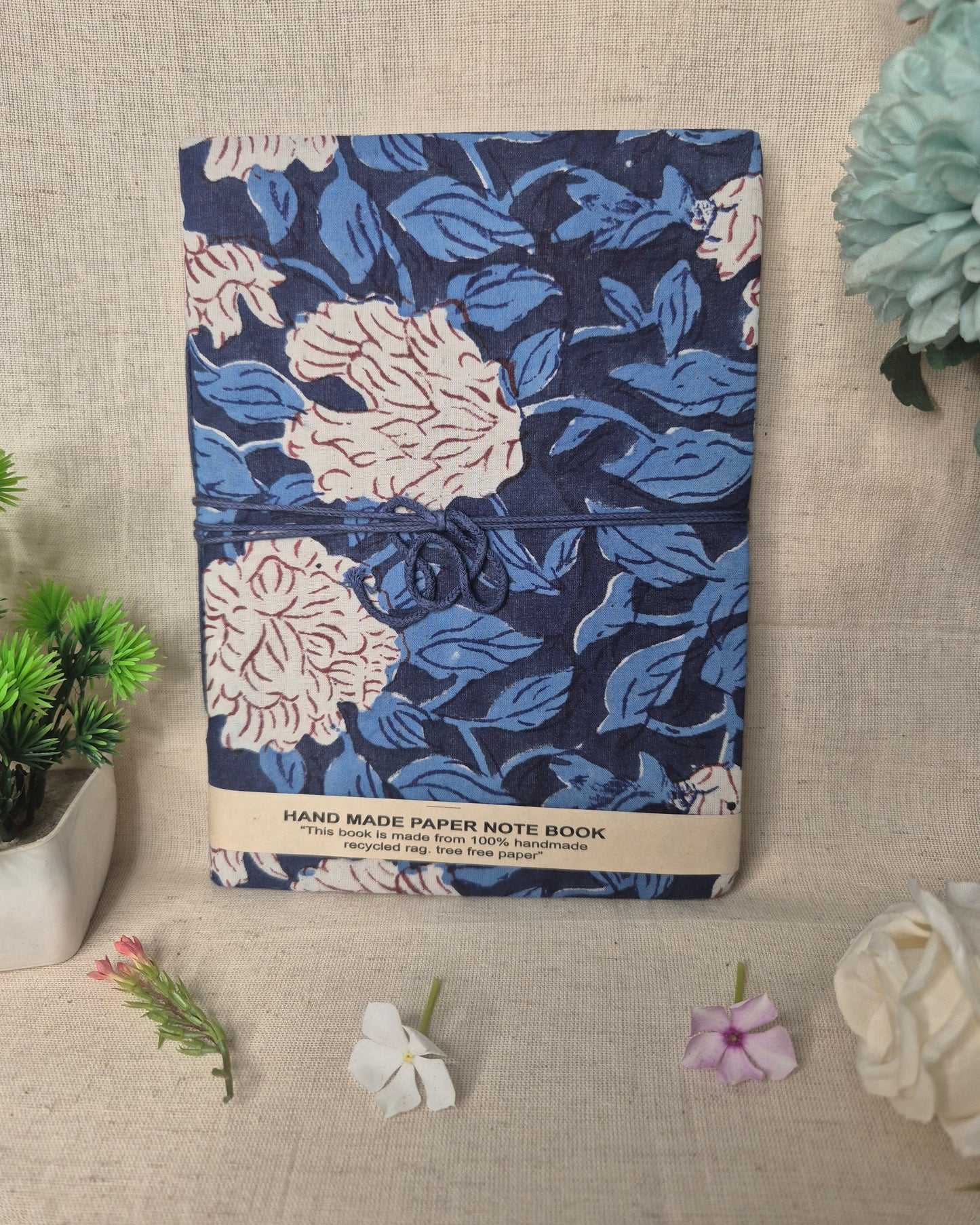 Floral patterned notebook on a textured surface with plants