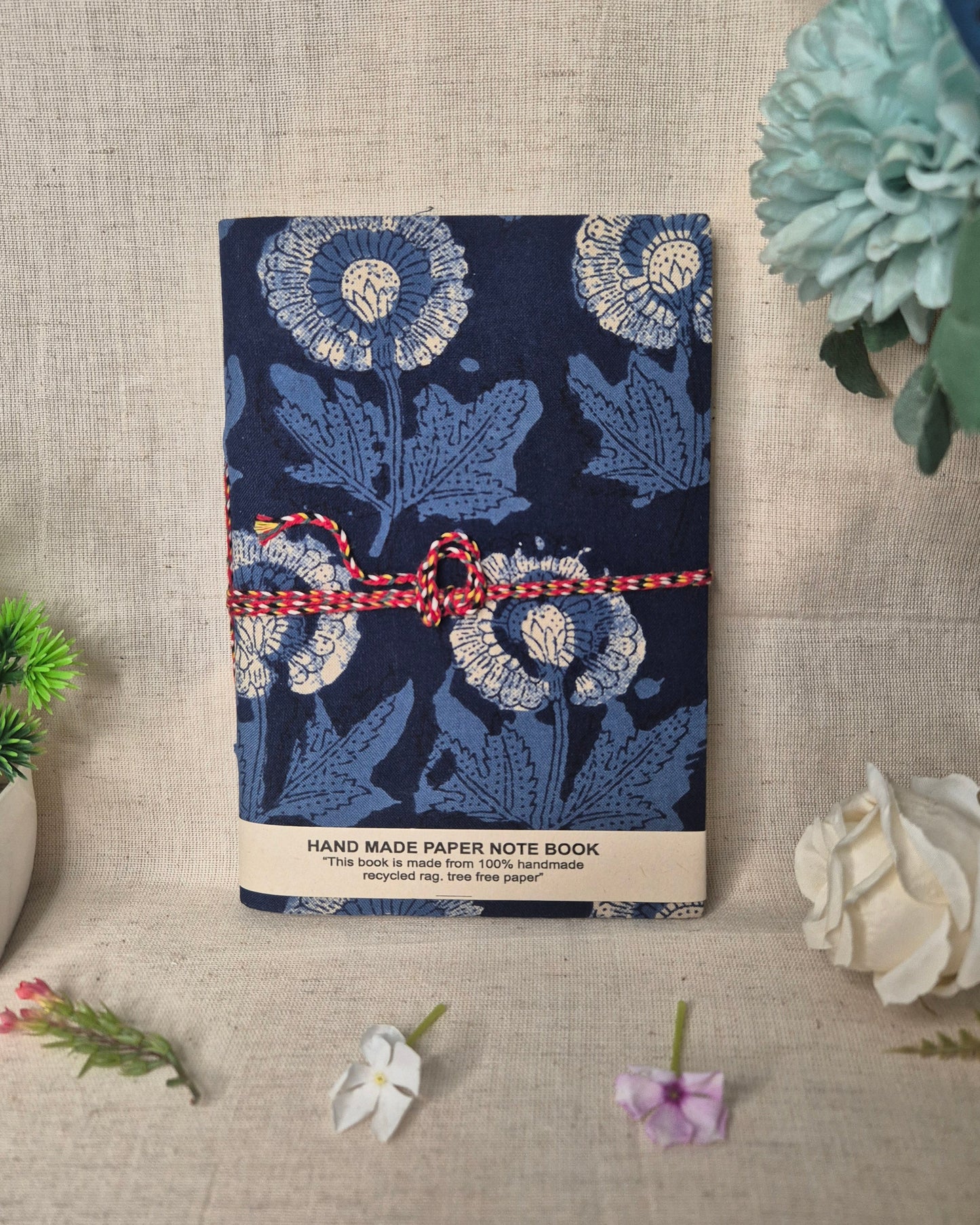 Blue floral notebook with a red string on a textured surface