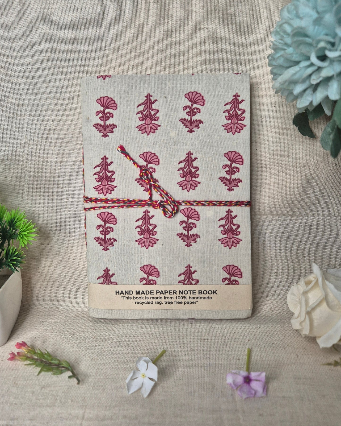 Handmade paper notebook with floral design on a textured surface .