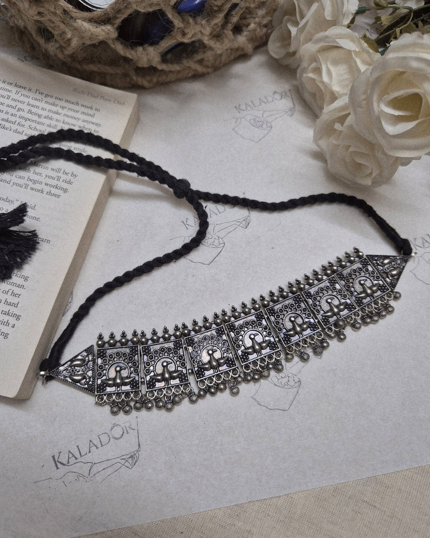 Decorative headband with intricate designs on a textured surface with flowers and a book.