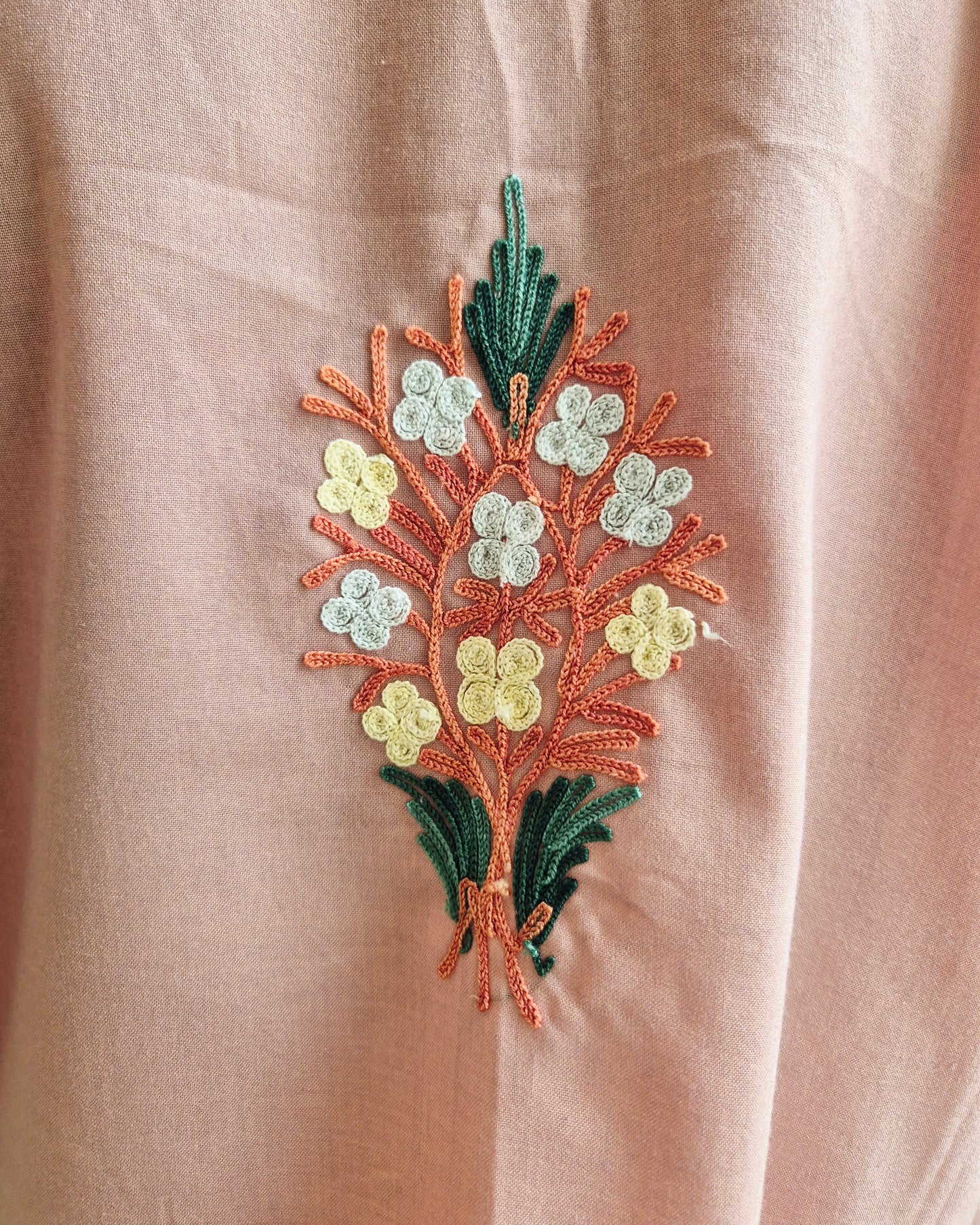Embroidered floral design on a beige fabric background