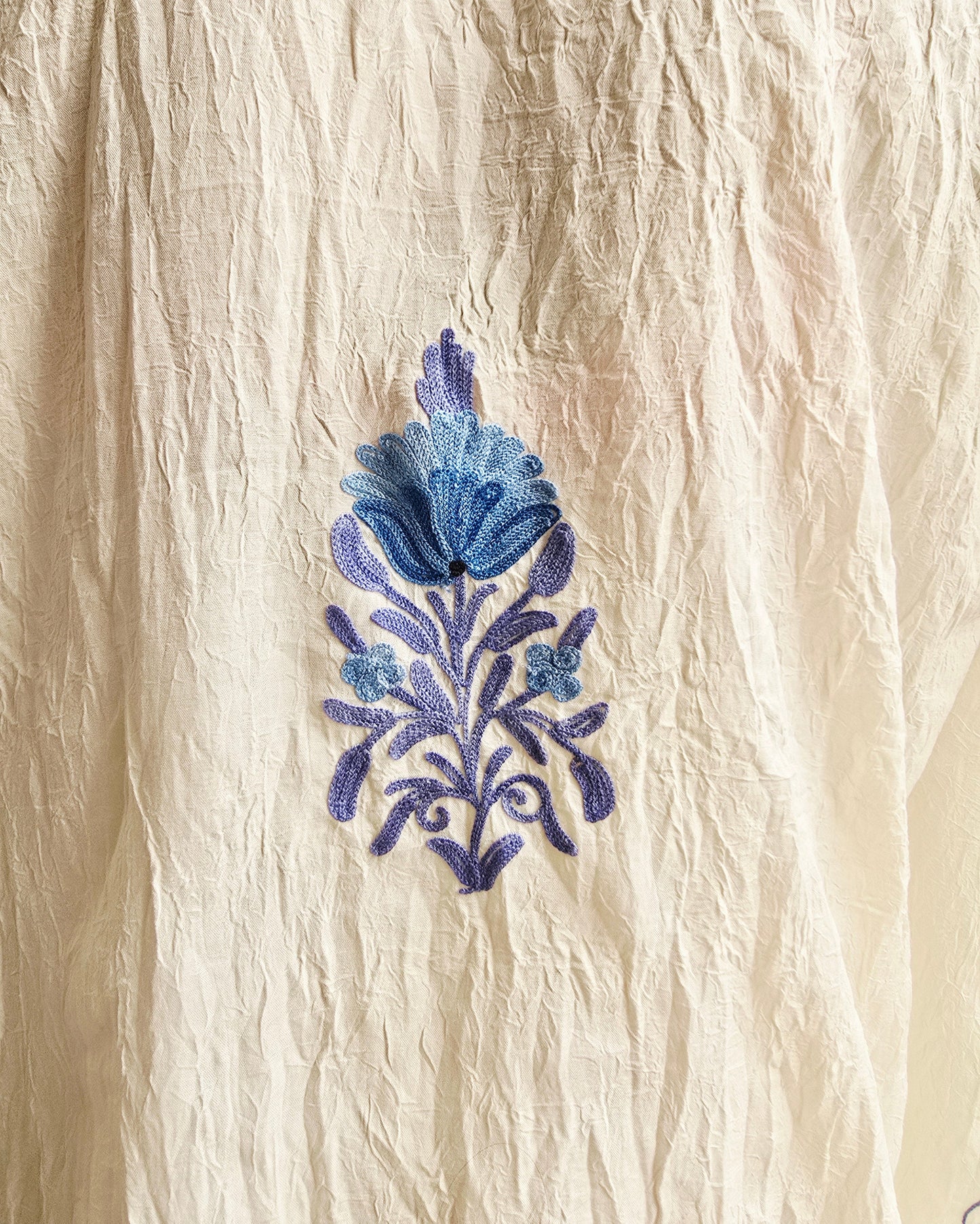 Blue floral embroidery on beige fabric