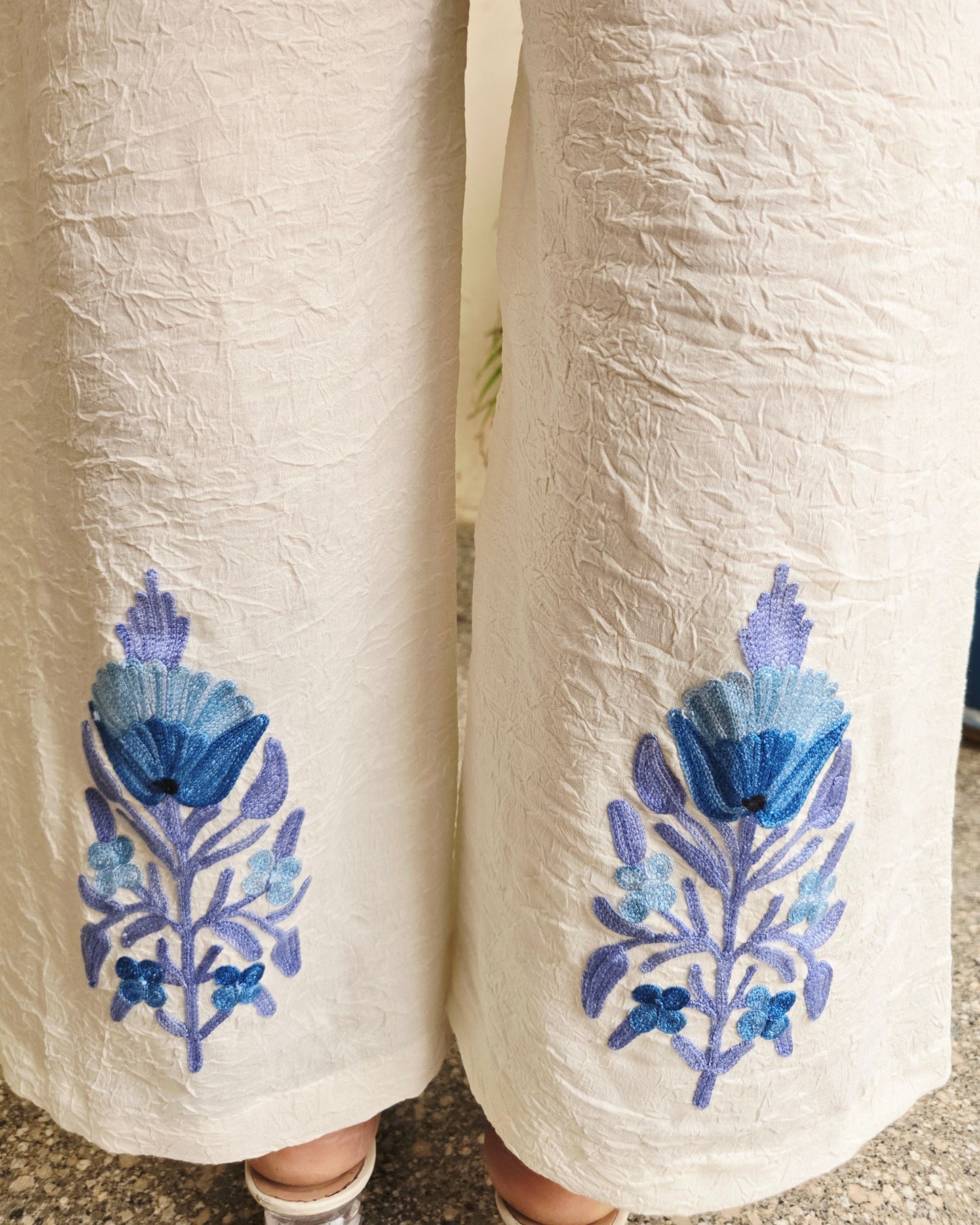 Two rolled-up pieces of fabric with blue floral embroidery on a textured surface.