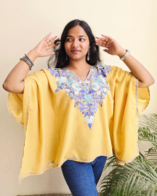 Woman wearing a yellow traditional outfit with floral patterns on a beige background