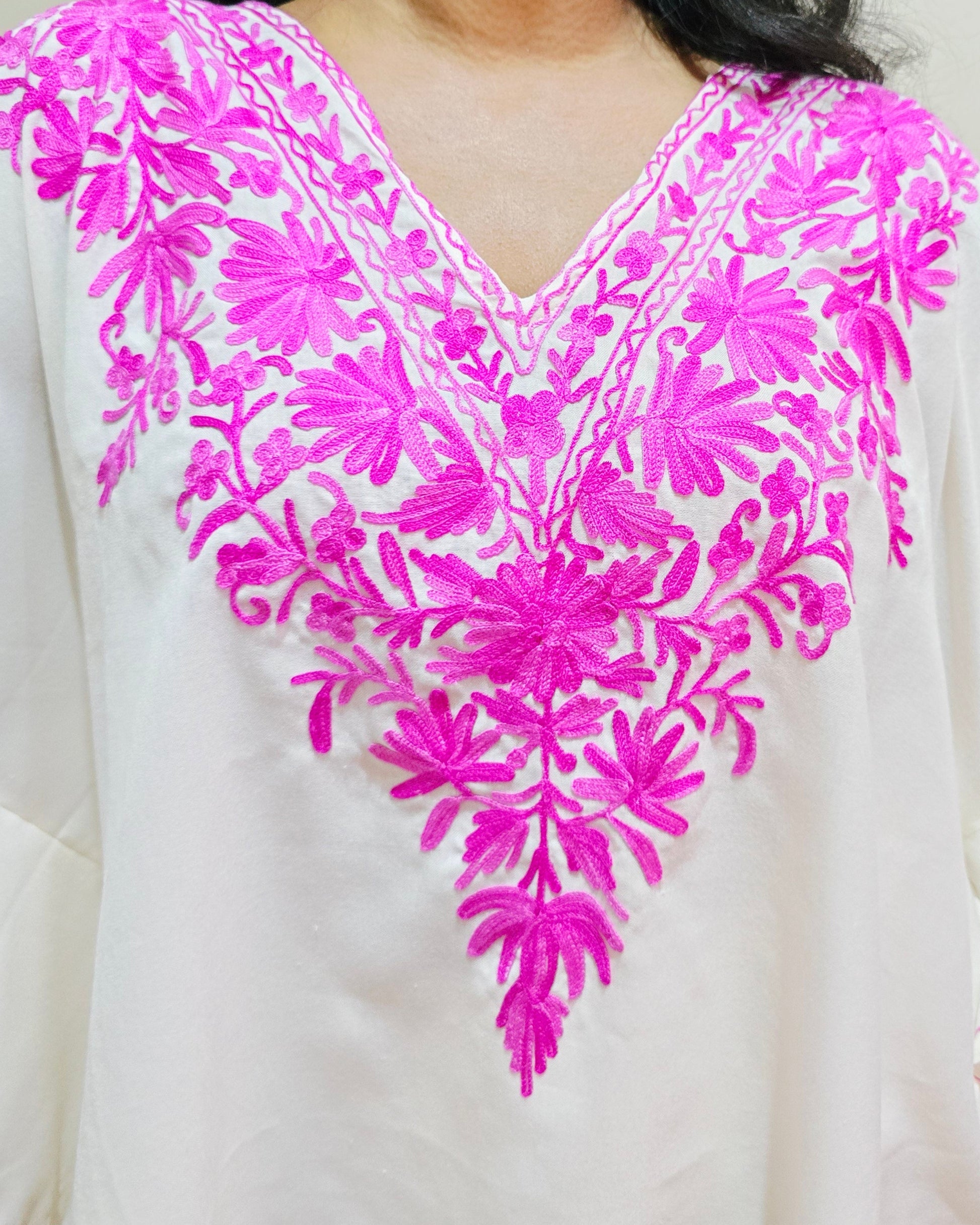 White garment with pink floral embroidery on a plain background