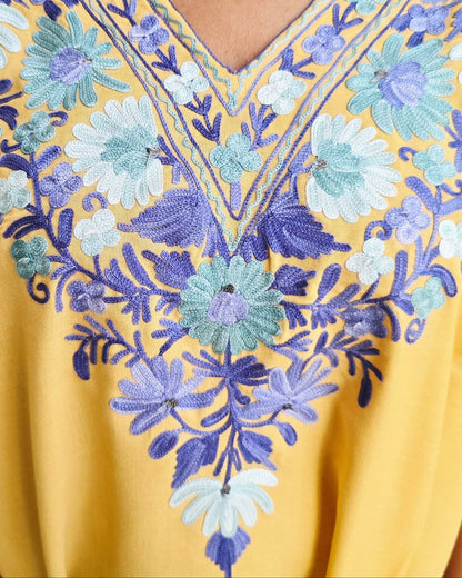Yellow top with blue floral embroidery on a neutral background