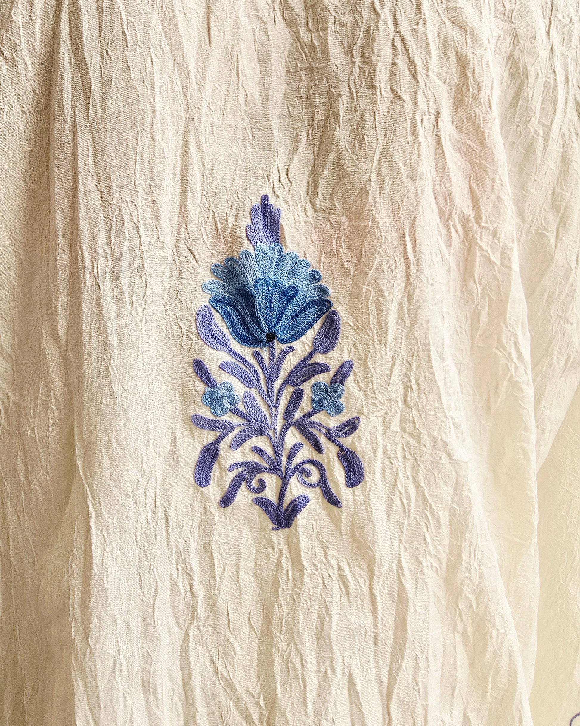 Blue floral embroidery on beige fabric