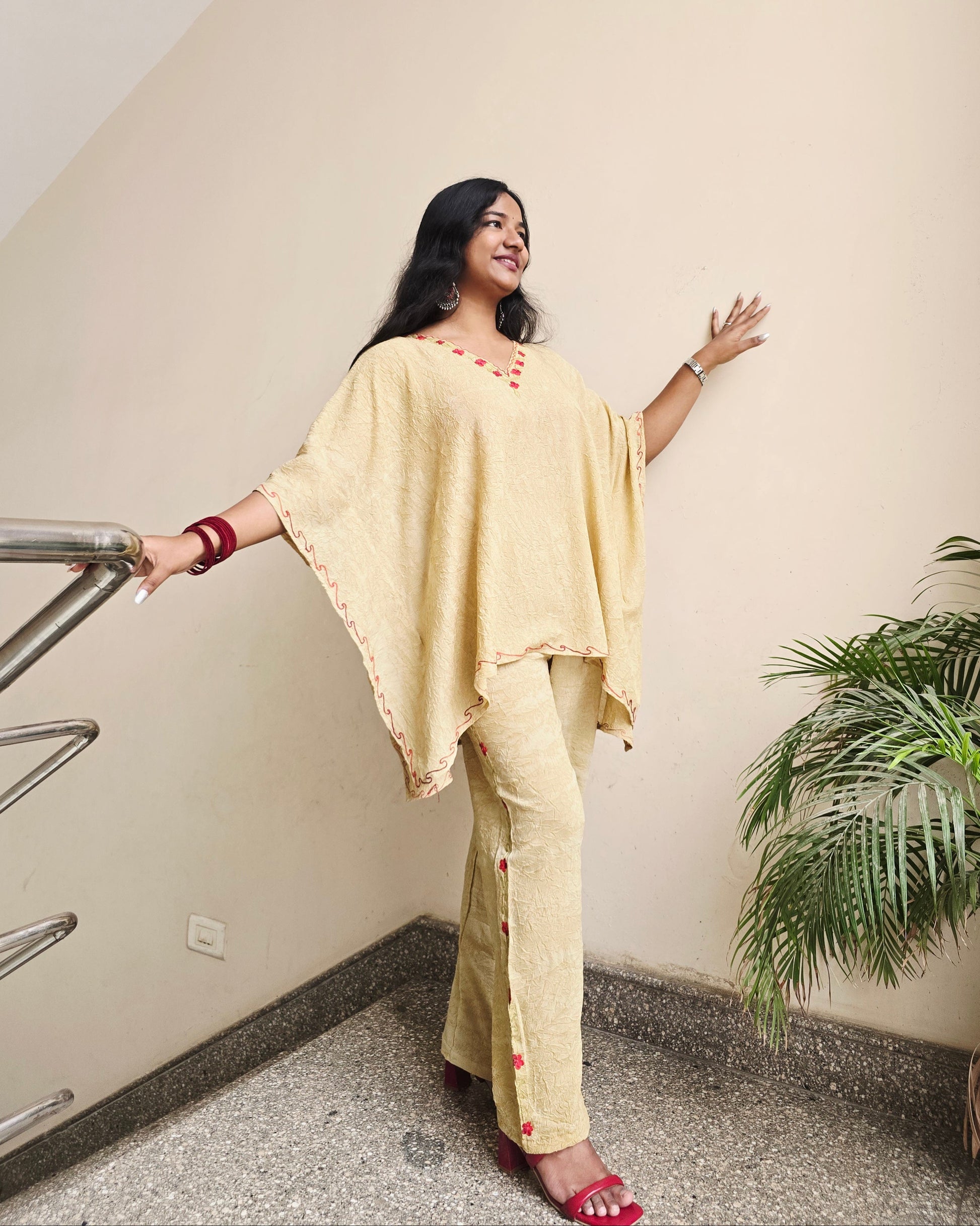 Person in a yellow outfit standing on a chair indoors with a plant in the background