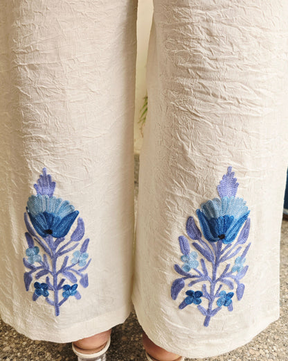 Two rolled-up pieces of fabric with blue floral embroidery on a textured surface.