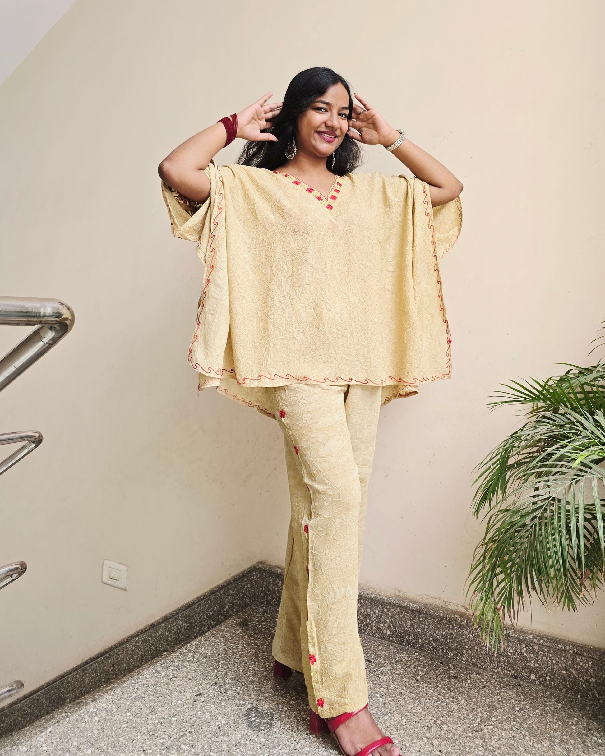 Woman in a yellow outfit standing indoors with a plant in the background