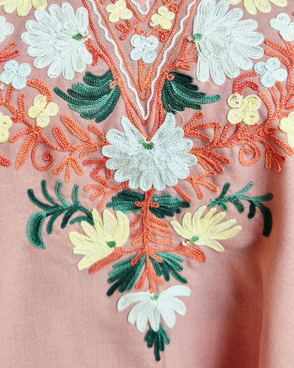 Close-up of floral embroidery on a garment with pink background