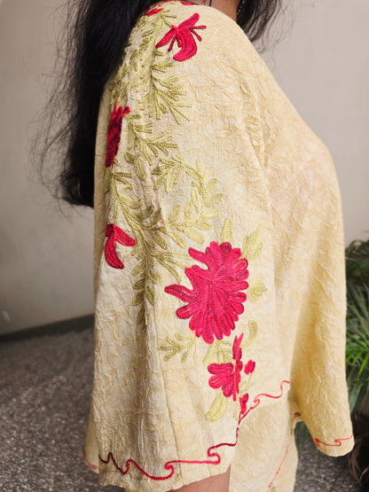 Beige oven mitt with red floral embroidery on a neutral background
