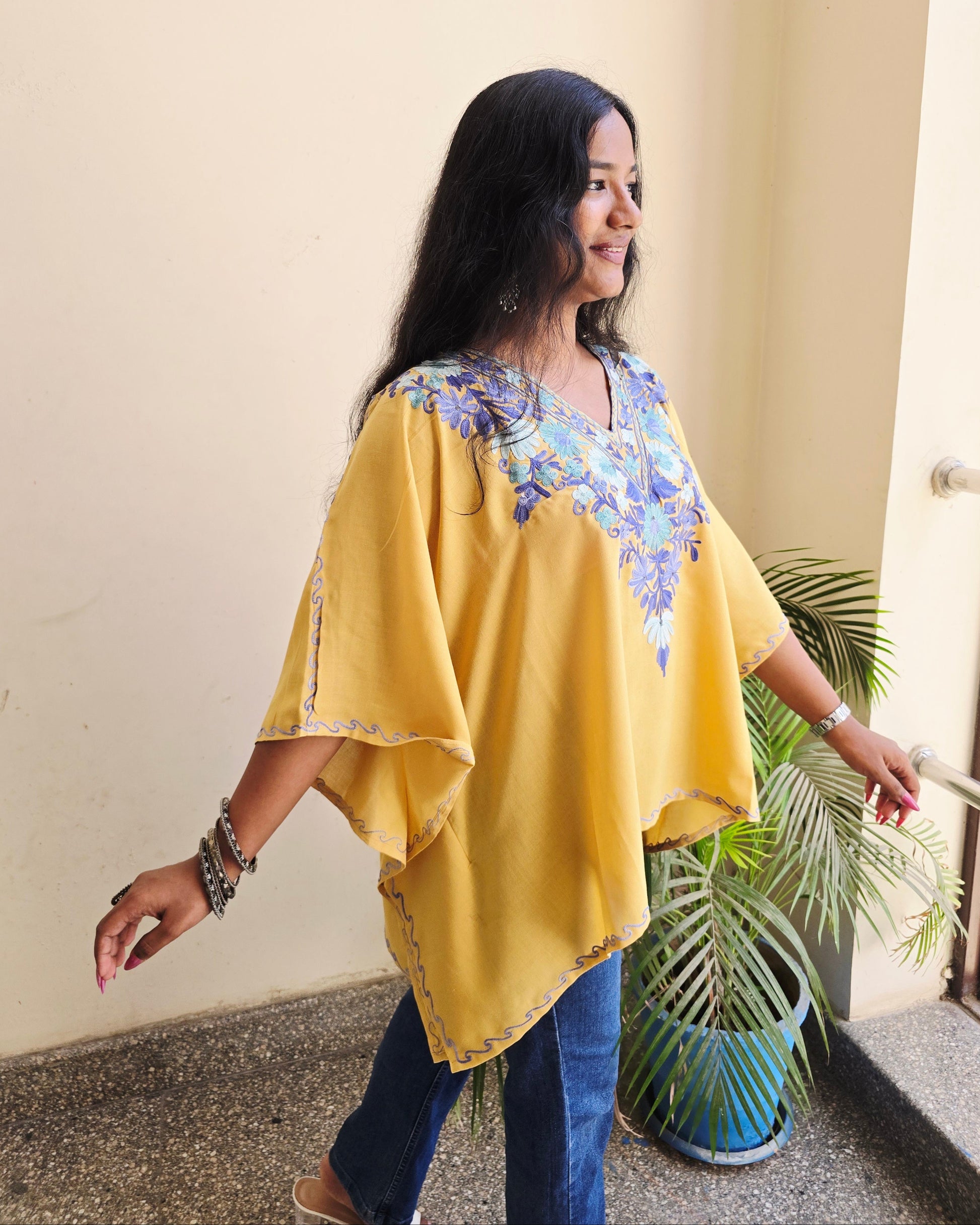 Person wearing a yellow outfit with a floral top, standing on a light-colored floor.