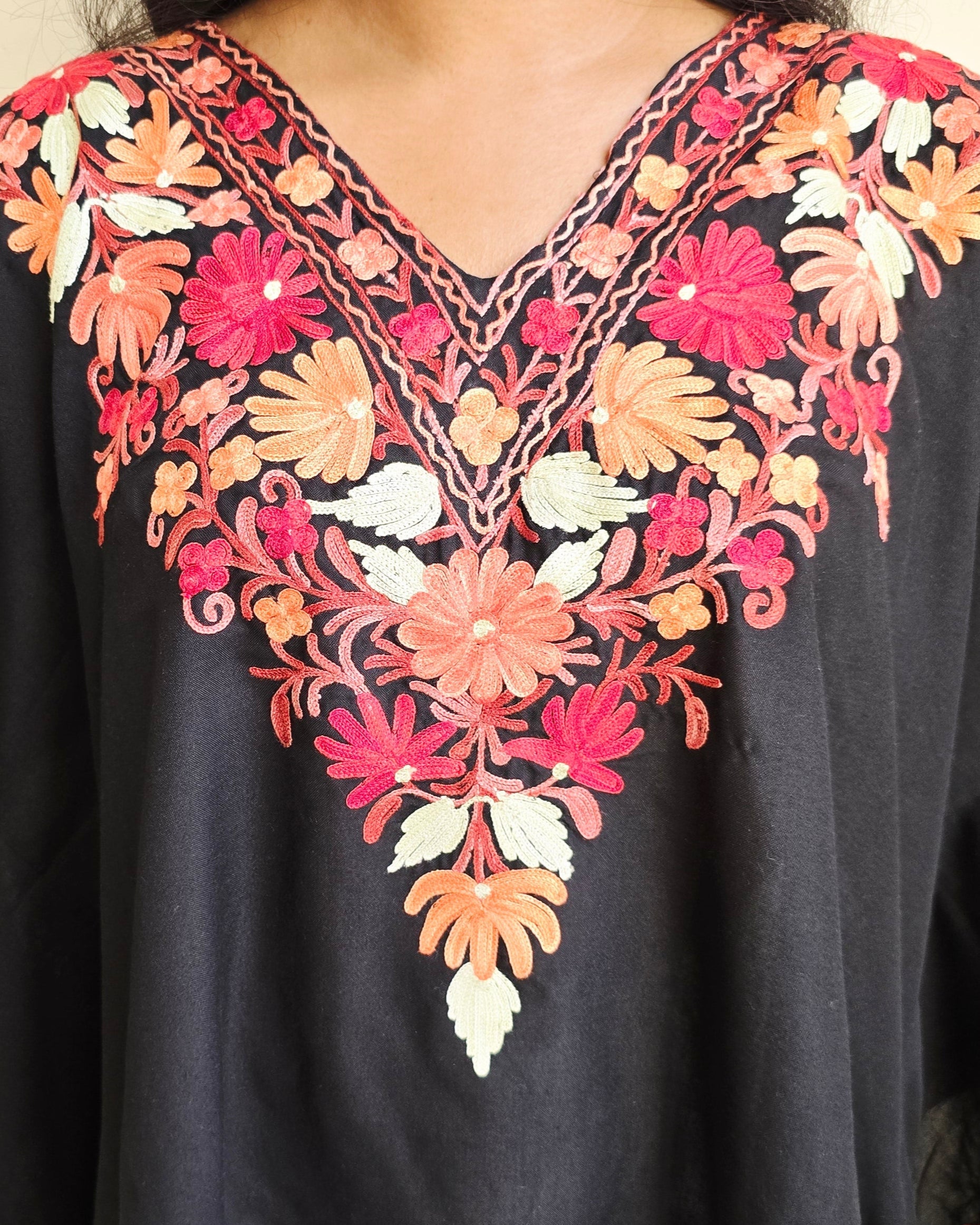 Black top with colorful floral embroidery on a beige background